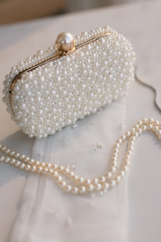 Elegant pearl clutch with pearl necklace laid out on soft fabric, capturing bridal accessories